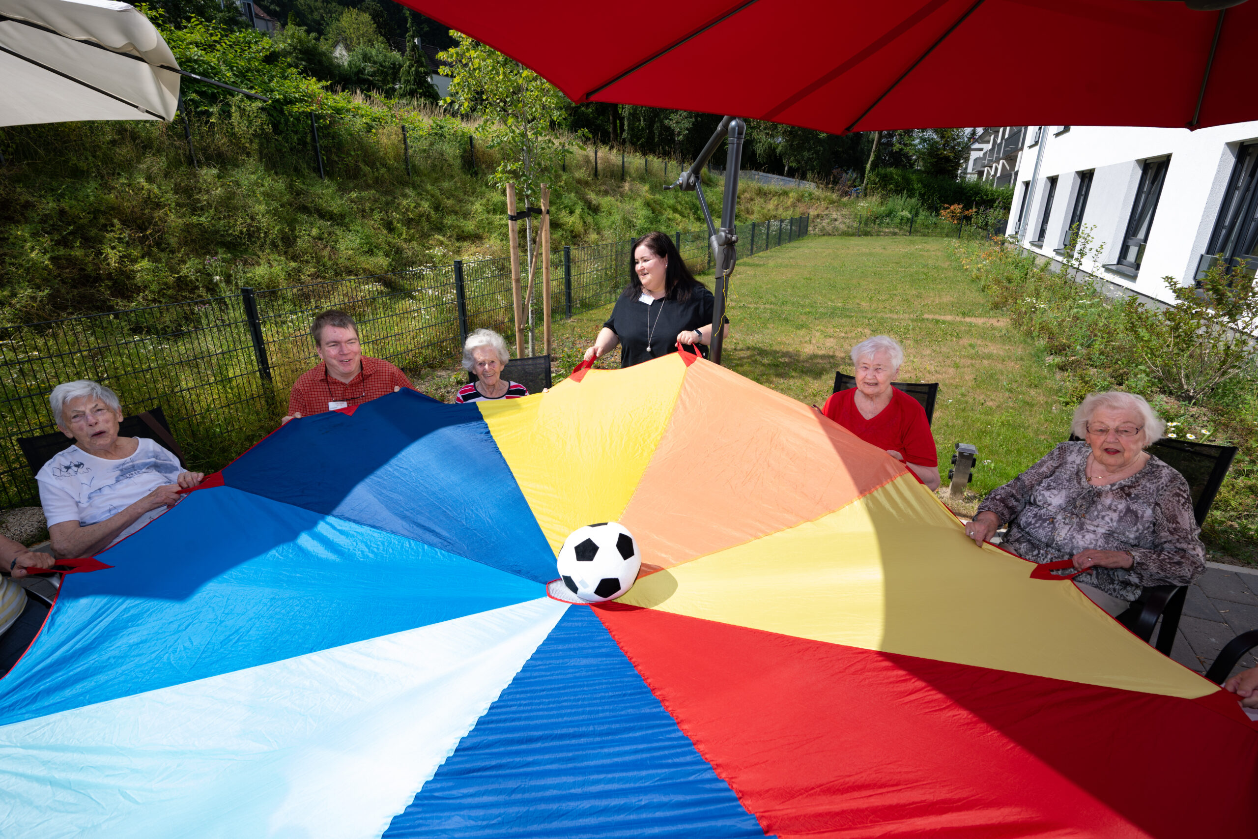 Personen spielen mit Ball und Schwungtuch.